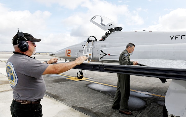 Fleet Readiness Center Southeast (FRCSE) Adversary Production Office Commander, Cmdr. Mitchell Conover, right, pre-flights an F-5N Tiger II as Plane Captain, Joe Hawley, stands by to answer questions prior to take off.