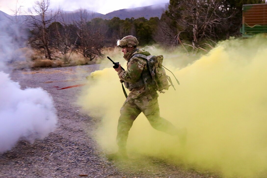A soldier runs through a cloud of yellow smoke.