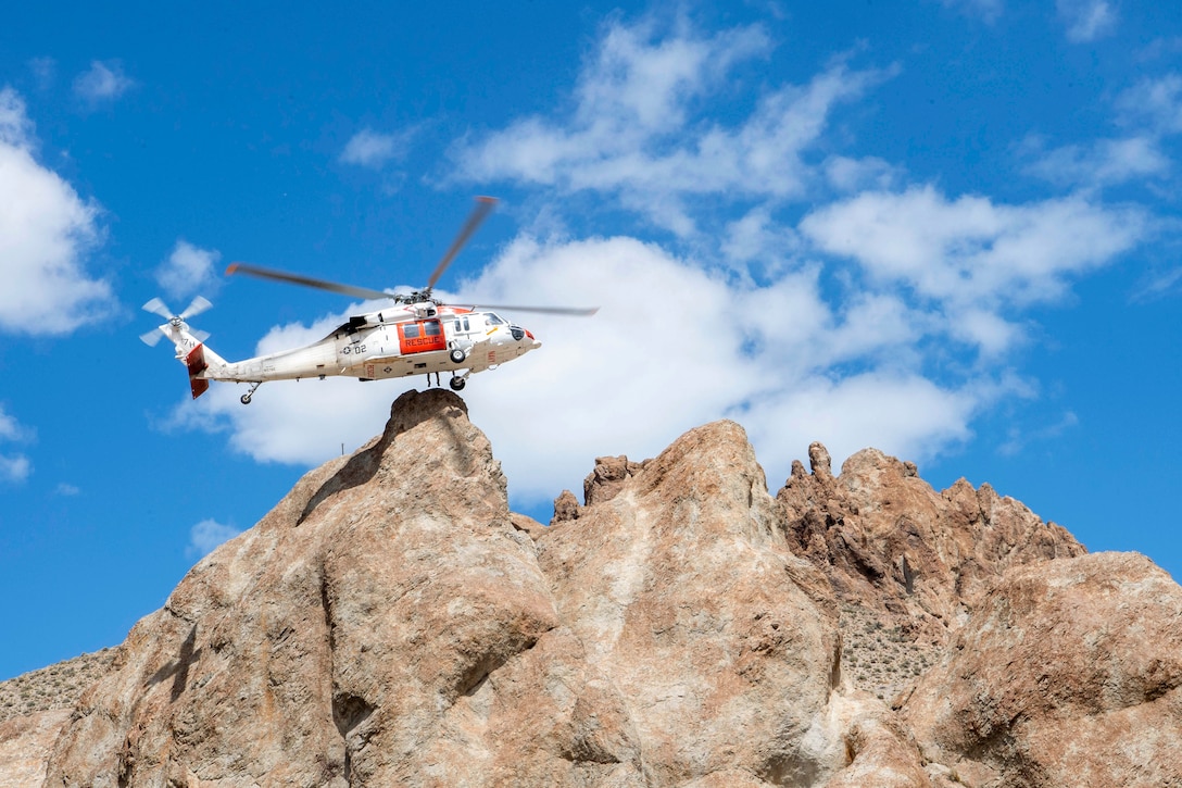 A helicopter flies over rocky terrain.