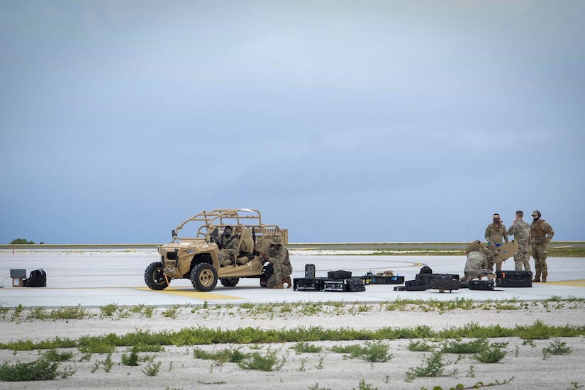 A vehicle and equipment is scattered about with troops milling nearby.