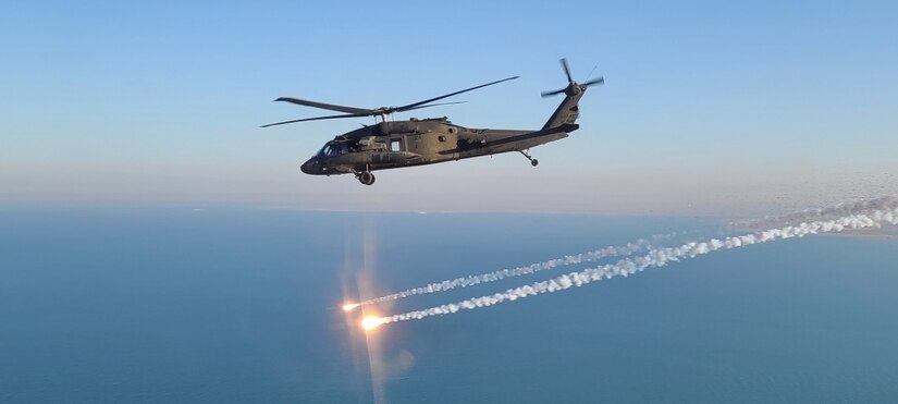 A UH-60 Black Hawk helicopter flies through a blue sky.