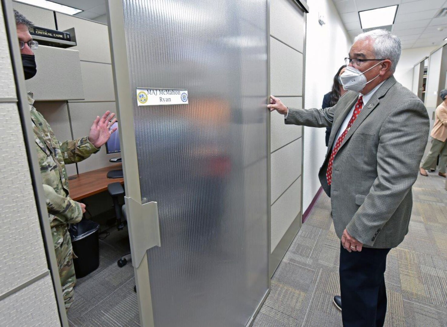 Maj. Ryan McMahon, professor of surgery and Director of Basic Life Support, demonstrates the sliding door of his new office partition to J.M. Harmon III, Deputy to the U.S. Army Medical Center of Excellence commanding general.