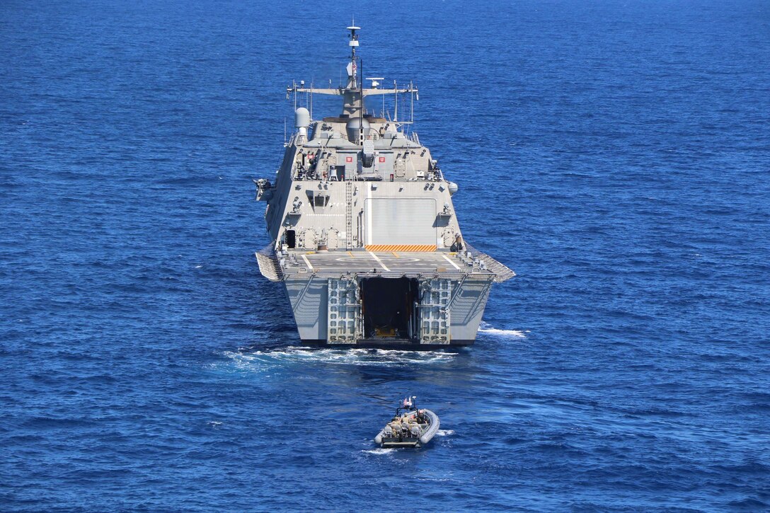 A ship travels ahead of an inflatable boat in the sea.