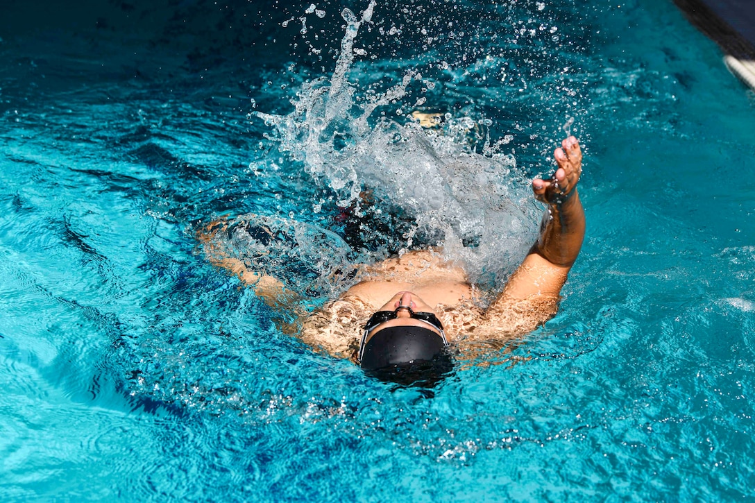 A Marine performs the backstroke in a pool.