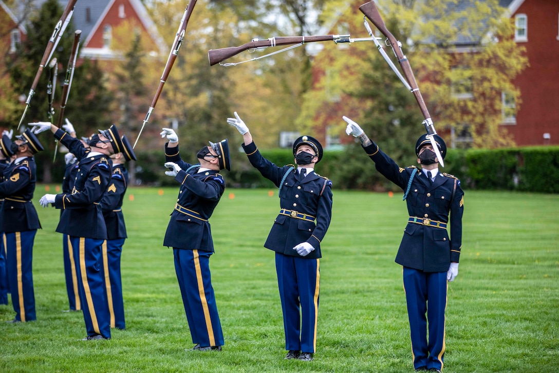 A group of soldiers twirl rifles in the air.