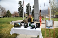 A female Soldier and a woman pose for a picture in front of photos