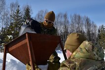 U.S. Air Force Staff Sgt. Tyler Kochlany, 354th Civil Engineer Squadron Explosive Ordnance Disposal (EOD) flight training NCOIC, left, and Staff Sgt. Kyle Brown, 354th Civil Engineer Squadron Explosive Ordnance Disposal (EOD) flight equipment NCOIC, fill bags with snow in preparation for a snow mitigation experiment March 18, 2021 at Eielson Air Force Base, Alaska.