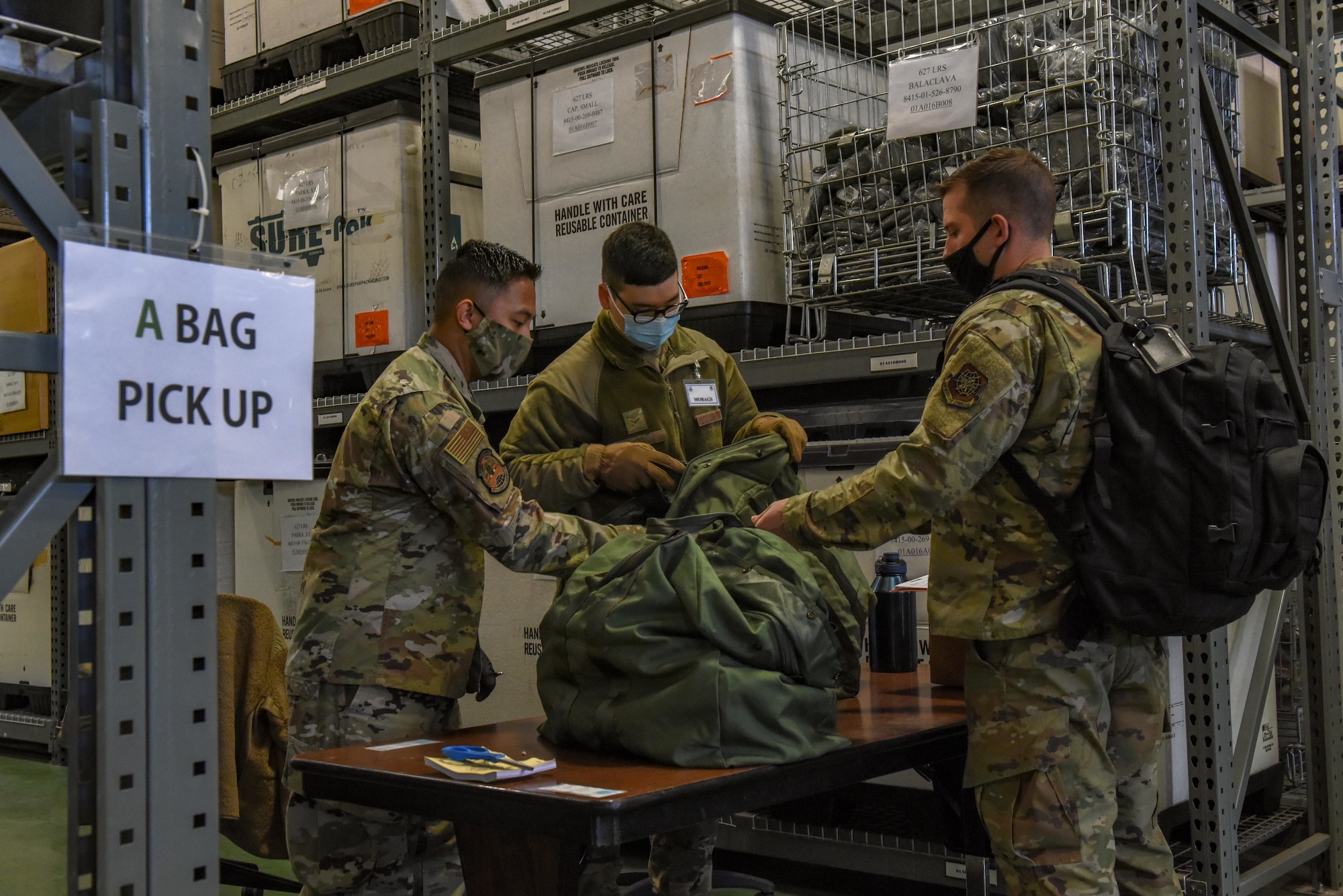 U.S. Air Force Senior Airman Isaiah Camacho, left, and U.S. Air Force Airman 1st Class Toby Yi, material management Airmen with the 627th Logistics Readiness Squadron, issue deployment gear to U.S. Air Force Staff Sgt. Dylan Hyde, a vehicle maintainer with the 62nd Maintenance Group, at a processing line as part of Exercise Rainer War at Joint Base Lewis-McChord, Washington, April 20, 2021. Exercise Rainier War tests the 62nd Airlift Wing’s capability to plan, generate and execute a deployment tasking, sustain contingency operations, demonstrate full spectrum readiness while in a contested, degraded and operationally limited environment. (U.S. Air Force photo by Airman Charles Casner)