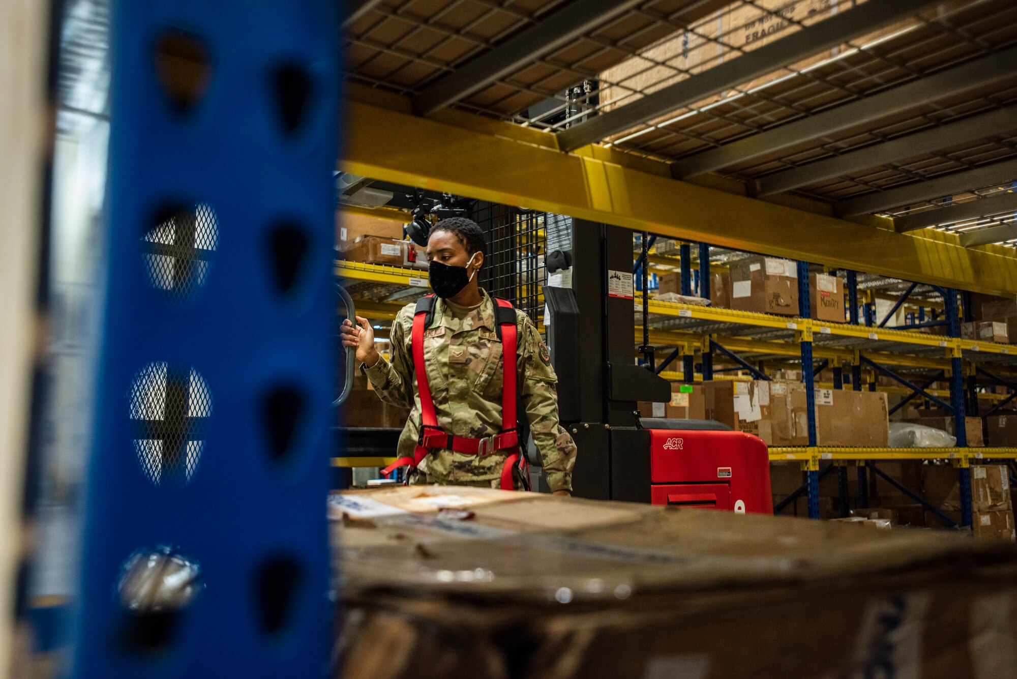 A female Airman exits a parked forklift.