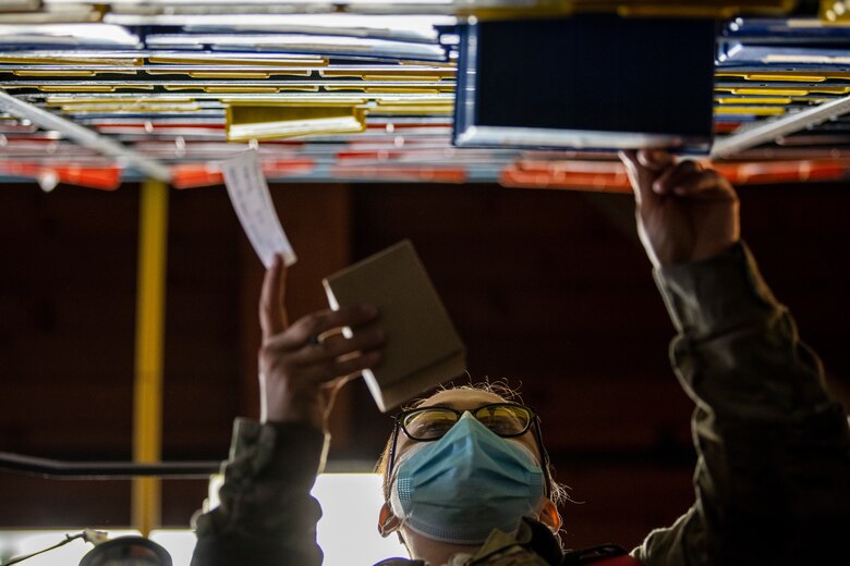 A female Airman is seen from a low angle of her taking a part from a shelf.