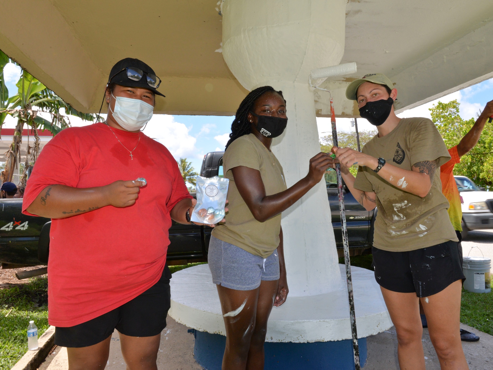 Chaunice Nauta, an Agat Mayor’s Office maintenance worker, shares local coconut candy with U.S. Air Force Senior Airman Alexis Northcutt, 36th Healthcare Operations Squadron medical logistics technician, and U.S. Air Force Staff Sgt. Kelly Lawson, 36th HCOS noncommissioned officer in charge of in-garrison maintenance, during a bus stop painting event in Agat, Guam, March 20, 2021. Nearly a dozen 36th HCOS Airmen and family members joined Agat Mayor’s Office staff to repaint two village bus stops through the Andersen Air Force Base Sister Village Sister Squadron program, in which squadron volunteers collaborate in events with Guam residents to strengthen their friendship and partnership. (U.S. Air Force photo by Alana Chargualaf)