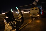 A loadmaster assigned to 352d Special Operations Wing assists marines from the 24th Marine Expeditionary Unit in off-loading a High Mobility Artillery Rocket System (HIMARS) onto an MC-130J Commando II at RAF Mildenhall on March 25, 2021 during low-visibility, night training.