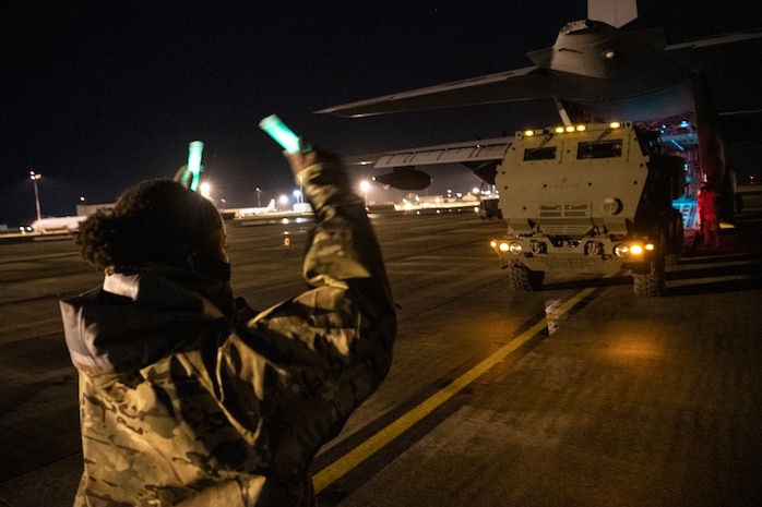 A loadmaster assigned to 352d Special Operations Wing assists marines from the 24th Marine Expeditionary Unit in off-loading a High Mobility Artillery Rocket System (HIMARS) onto an MC-130J Commando II at RAF Mildenhall on March 25, 2021 during low-visibility, night training.