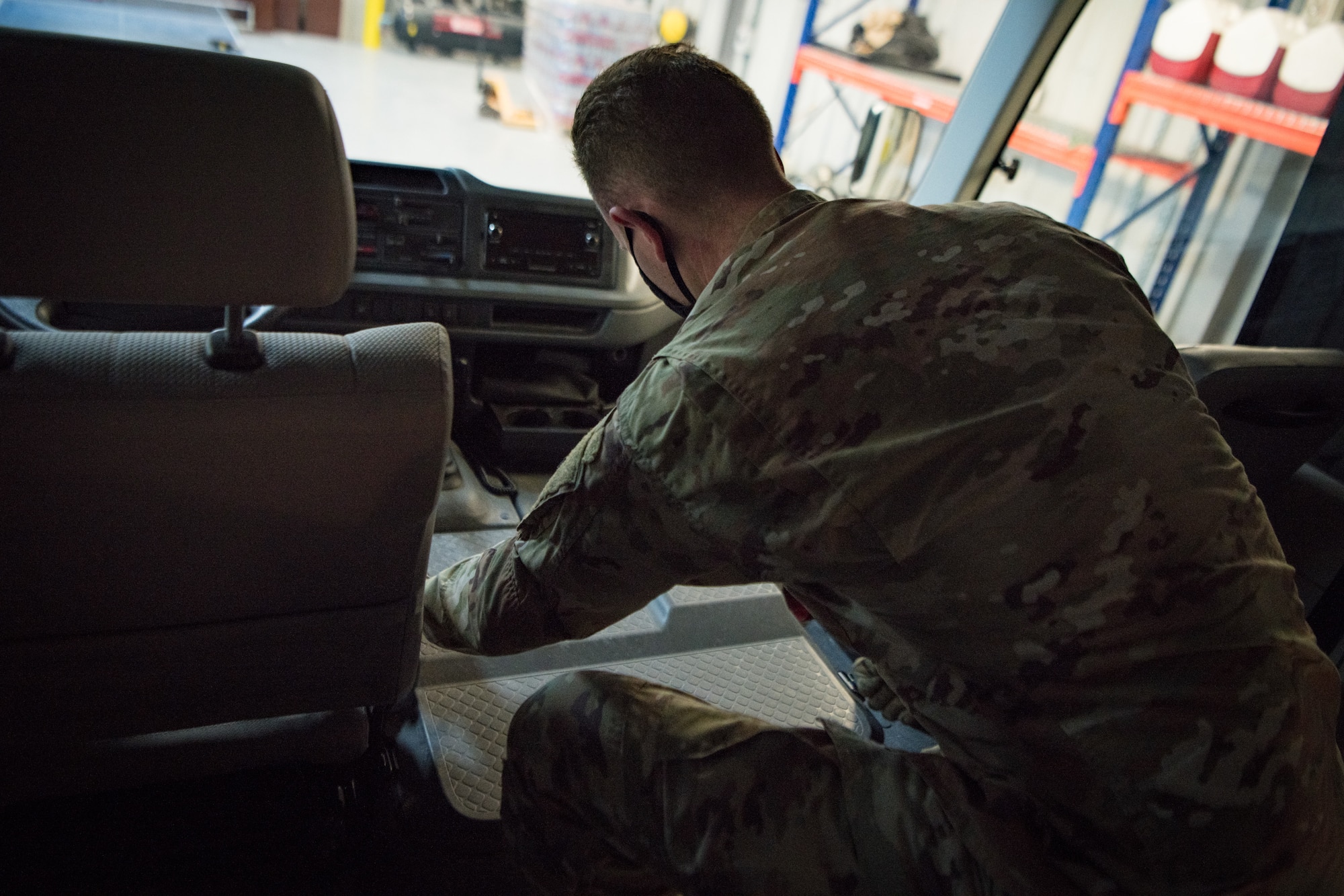 An airman replaces an engine cover on a bus