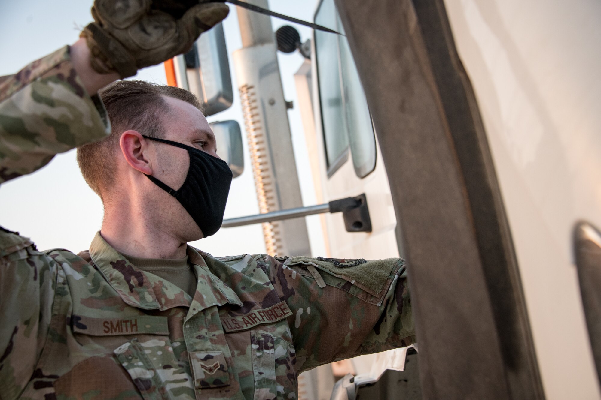 an airman removes a dipstick to inspect oil levels on a tractor trailer