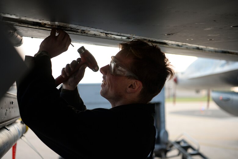 A maintainer performs maintenance on a jet.