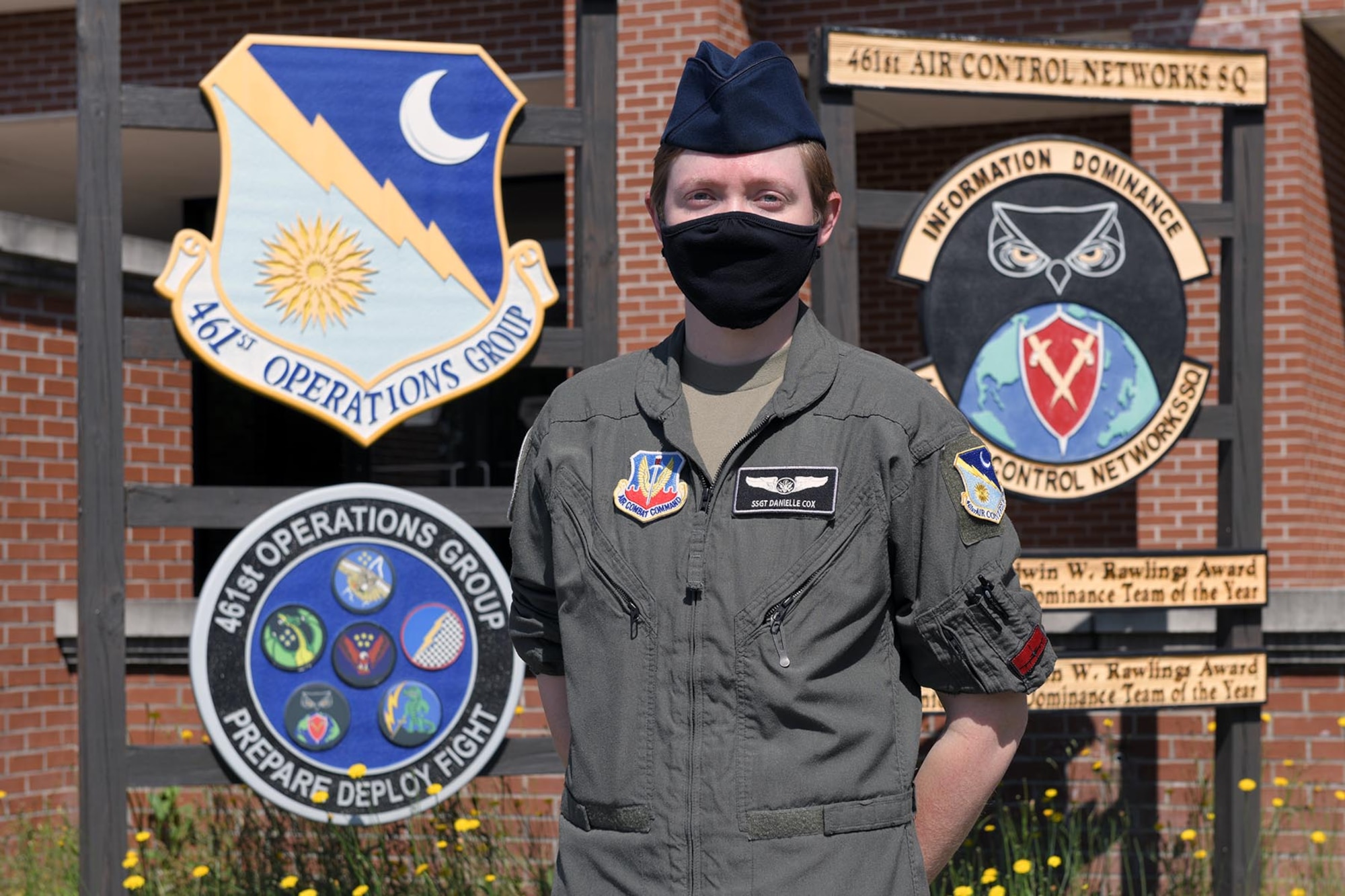 Photo show female Airmen standing in front of Group and Squadron signs outside building.