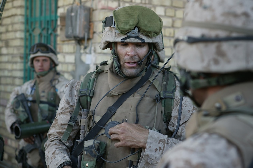 A Marine in combat gear speaks into a headset.