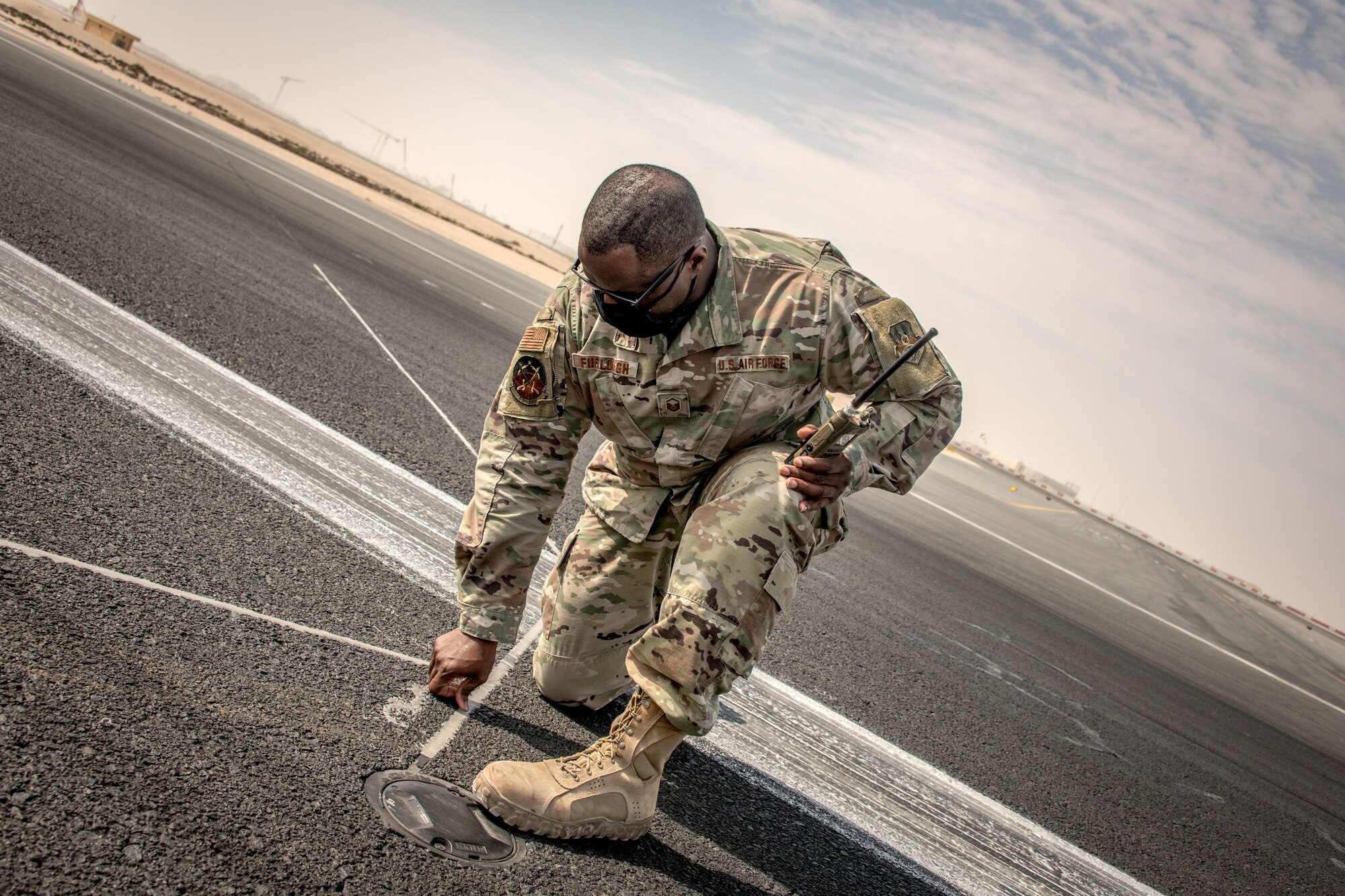 a man kneels on a flightline