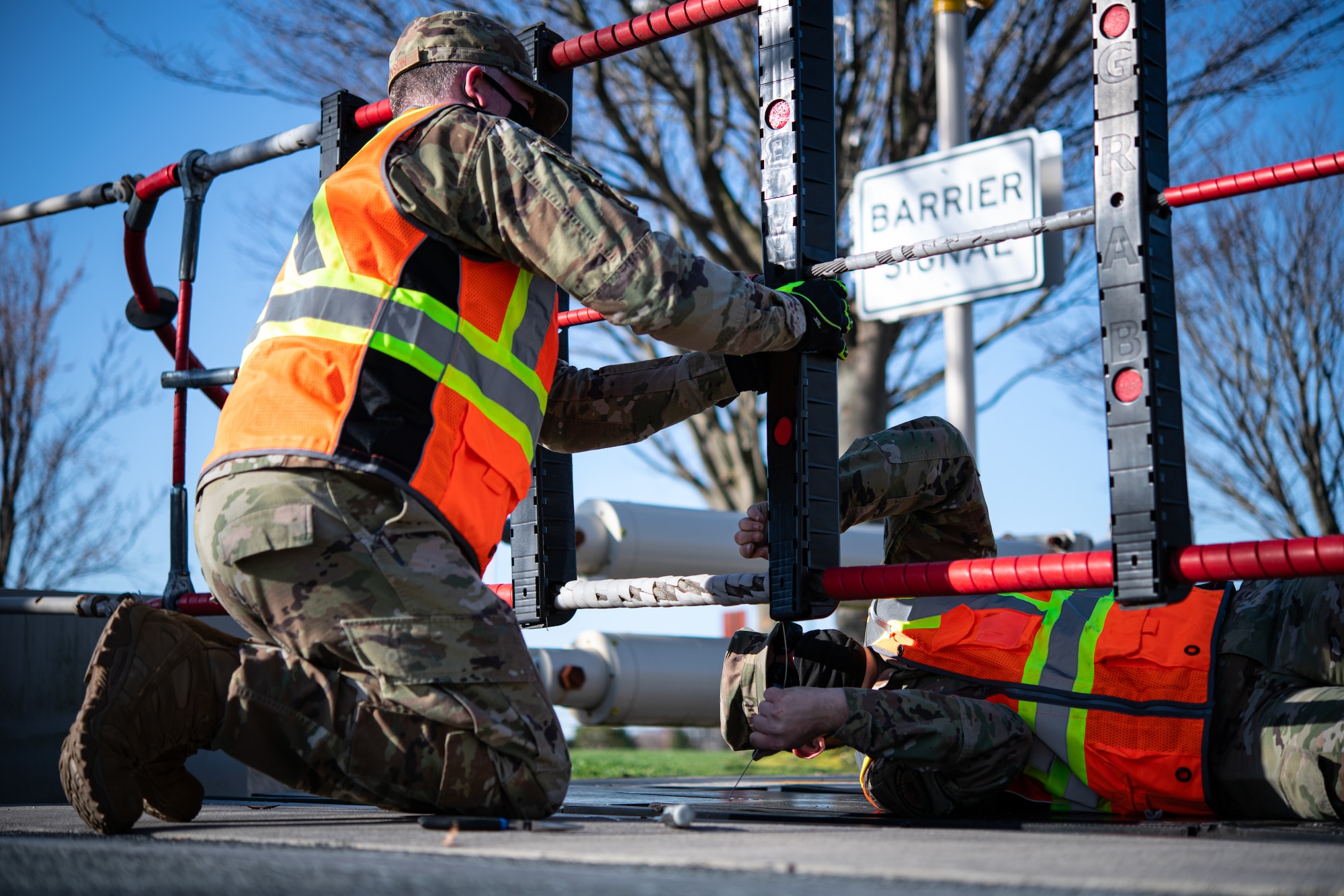Master Sgt. Trevor Wilkinson, left, 436th Civil Engineer Squadron noncommissioned officer in charge of electrical power production, and Senior Airman James Wolfley, 436th CES electrical power production journeyman,  replace plastic encasings from a ground automobile retractable barrier (GRAB) net, at Dover Air Force Base, Delaware, April 3, 2021. Encasings must be serviced periodically due to weather conditions and the constant pressure they receive when driven over by vehicles. (U.S. Air Force photo by Senior Airman Marco A. Gomez)