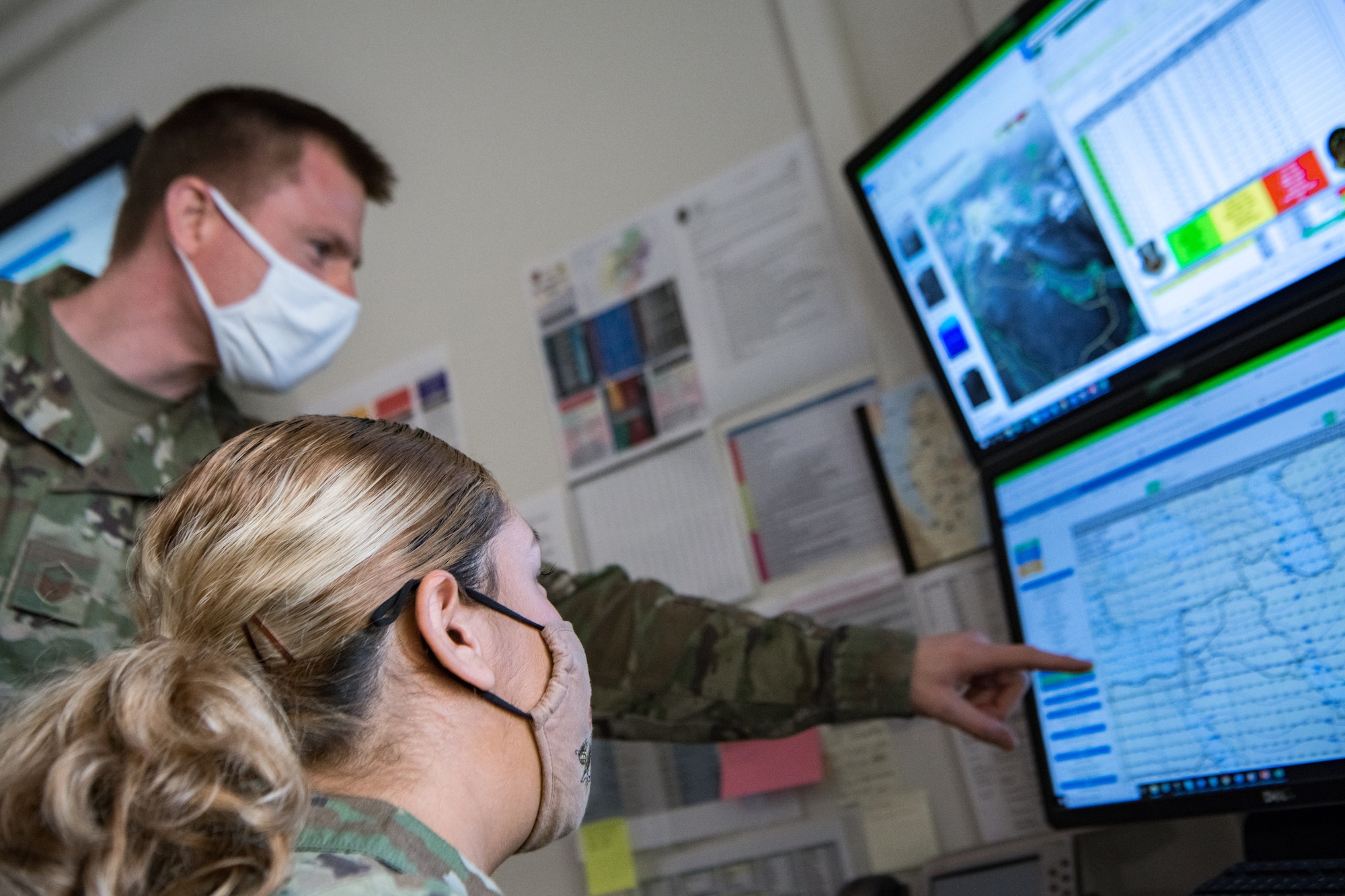 two airmen look at maps on computer screens