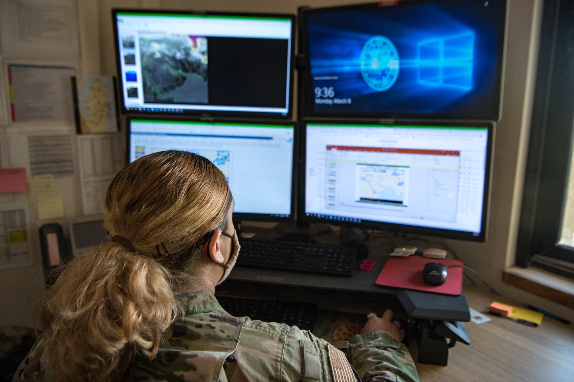 An airman sits in front of computer screens