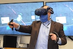 IMAGE: Naval Surface Warfare Center Dahlgren Division (NSWCDD) Technical Director John Fiore interacts with a concept captured in virtual reality that would enable the collection, curation, collaboration and conduction of Next Generation Combat Information Center (CIC) data and missions. Fiore engaged in the immersive experience made possible by the Next Generation CIC Tactical Advancements for the Next Generation Project developed by Johns Hopkins Applied Physics Lab scientists and sponsored by the Missile Defense Agency to create engagement and awareness around CIC possibilities through speculative design, looking ahead to 20 years in the future.