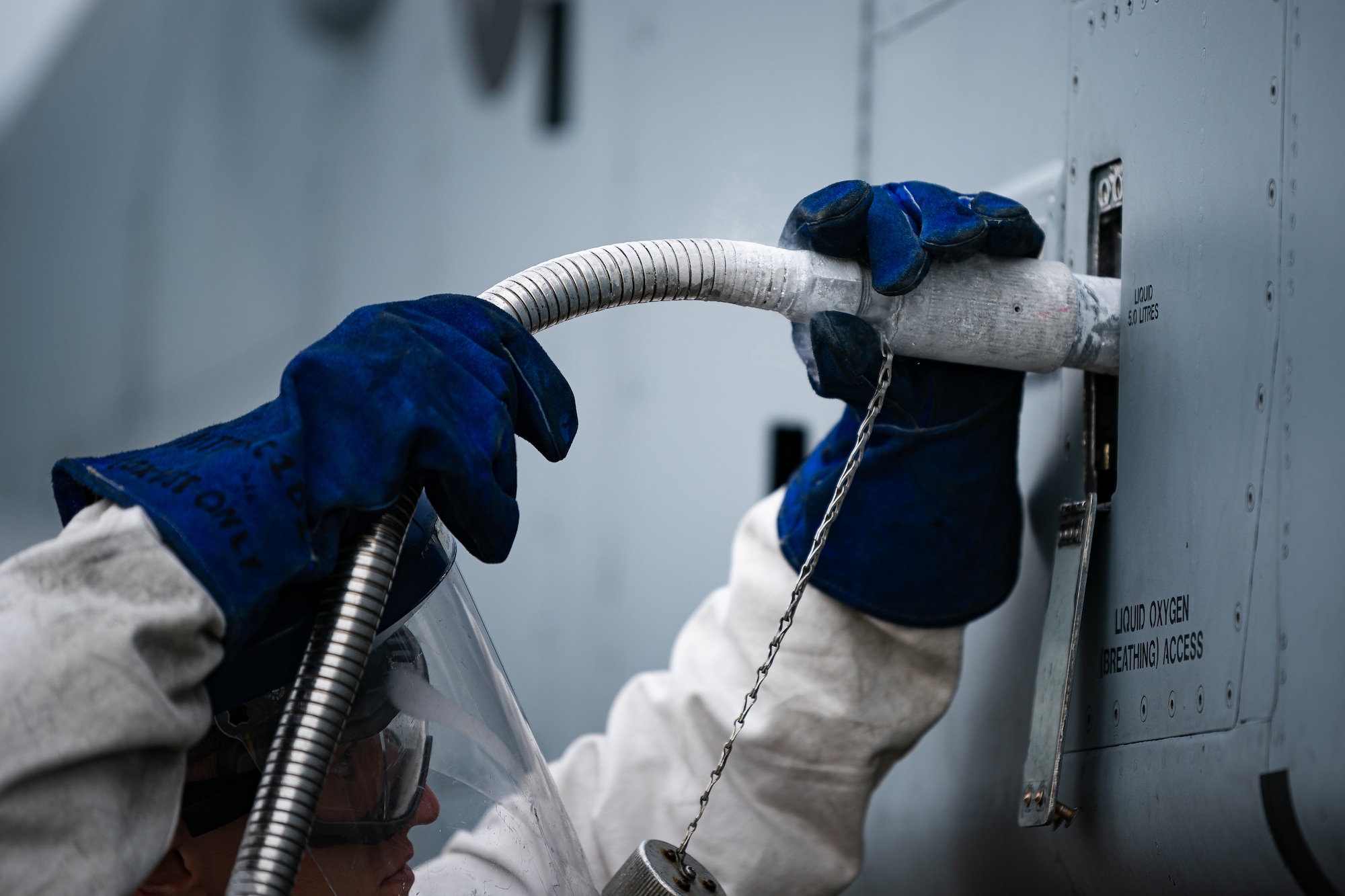 A photo of an Airman connecting a liquid oxygen hose to an aircraft