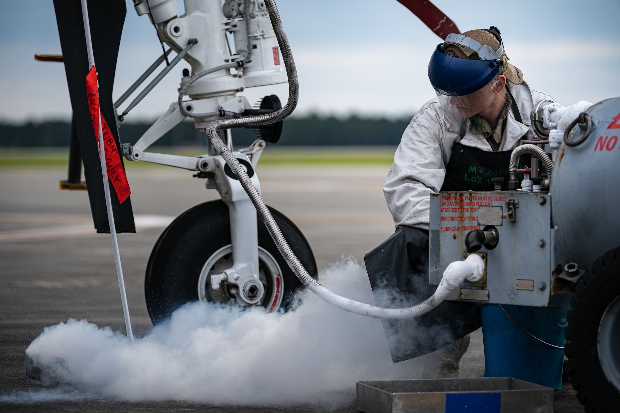 A photo of an Airman observing liquid oxygen as it vents from an aircraft
