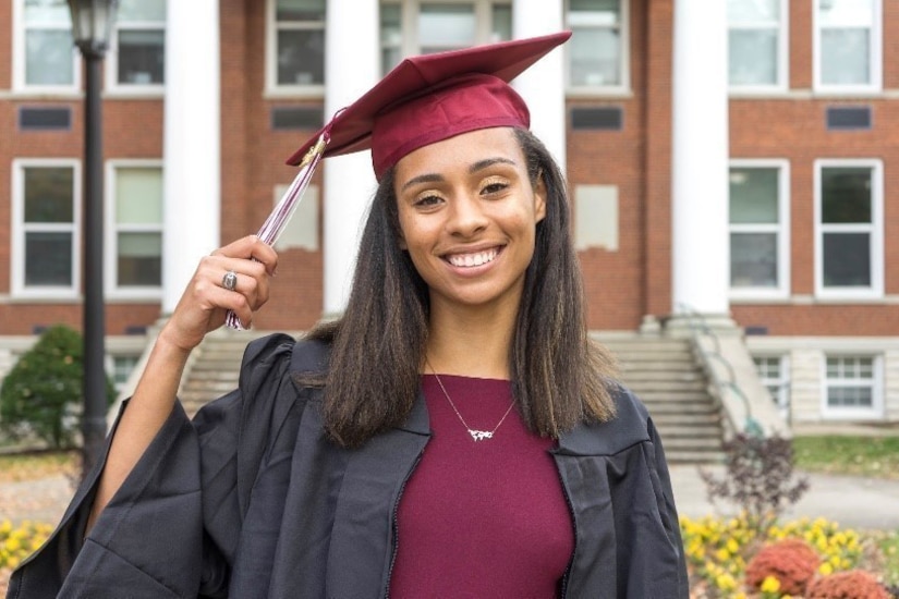 A woman poses with a cap and gown during her graduation.