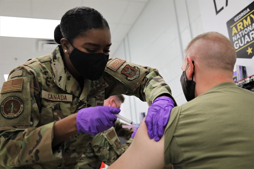 A woman gives an injection to a man.