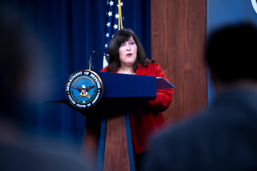 A woman stands at a lectern.