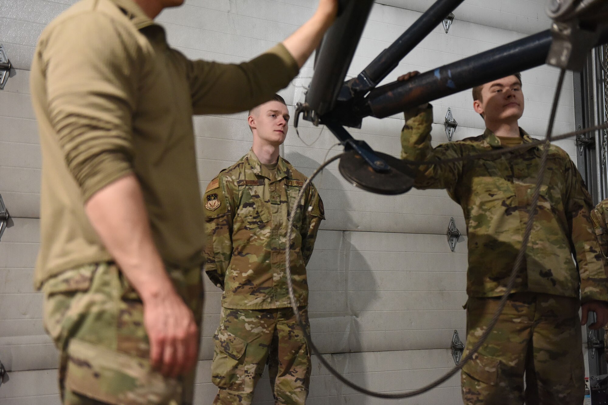 An inspector watches two Airmen prepare the booster for a roll transfer.
