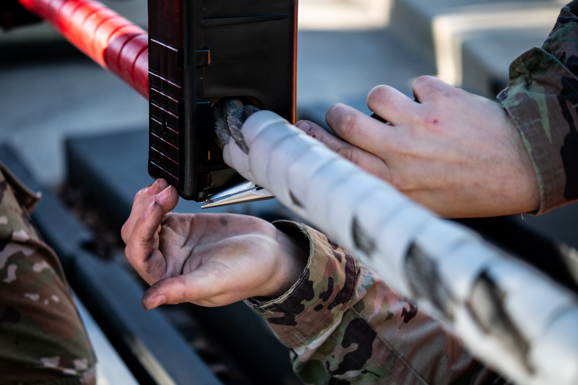 Senior Airman James Wolfley, 436th Civil Engineer Squadron electrical power production journeyman, inserts a metal wire into an encasing for a ground automobile retractable barrier (GRAB) net, at Dover Air Force Base, Delaware, April 3, 2021. The power production team conducts monthly maintenance on the GRAB net to ensure it functions properly in case of an emergency at the main gate. (U.S. Air Force photo by Senior Airman Marco A. Gomez)