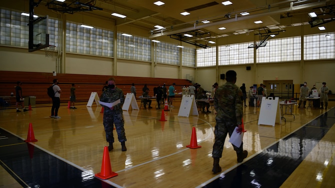 Airmen stand around waiting to get tested for COVID-19.