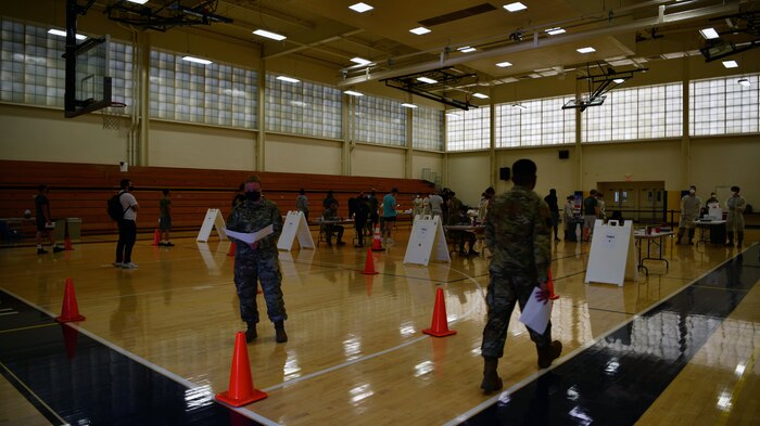 Airmen stand around waiting to get tested for COVID-19.