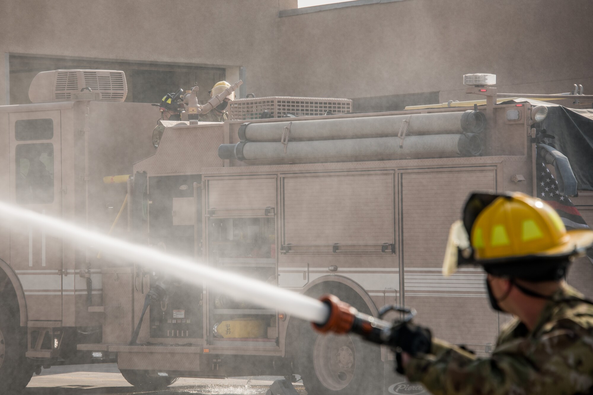 a firefighter sprays a hose with firefighters in the background