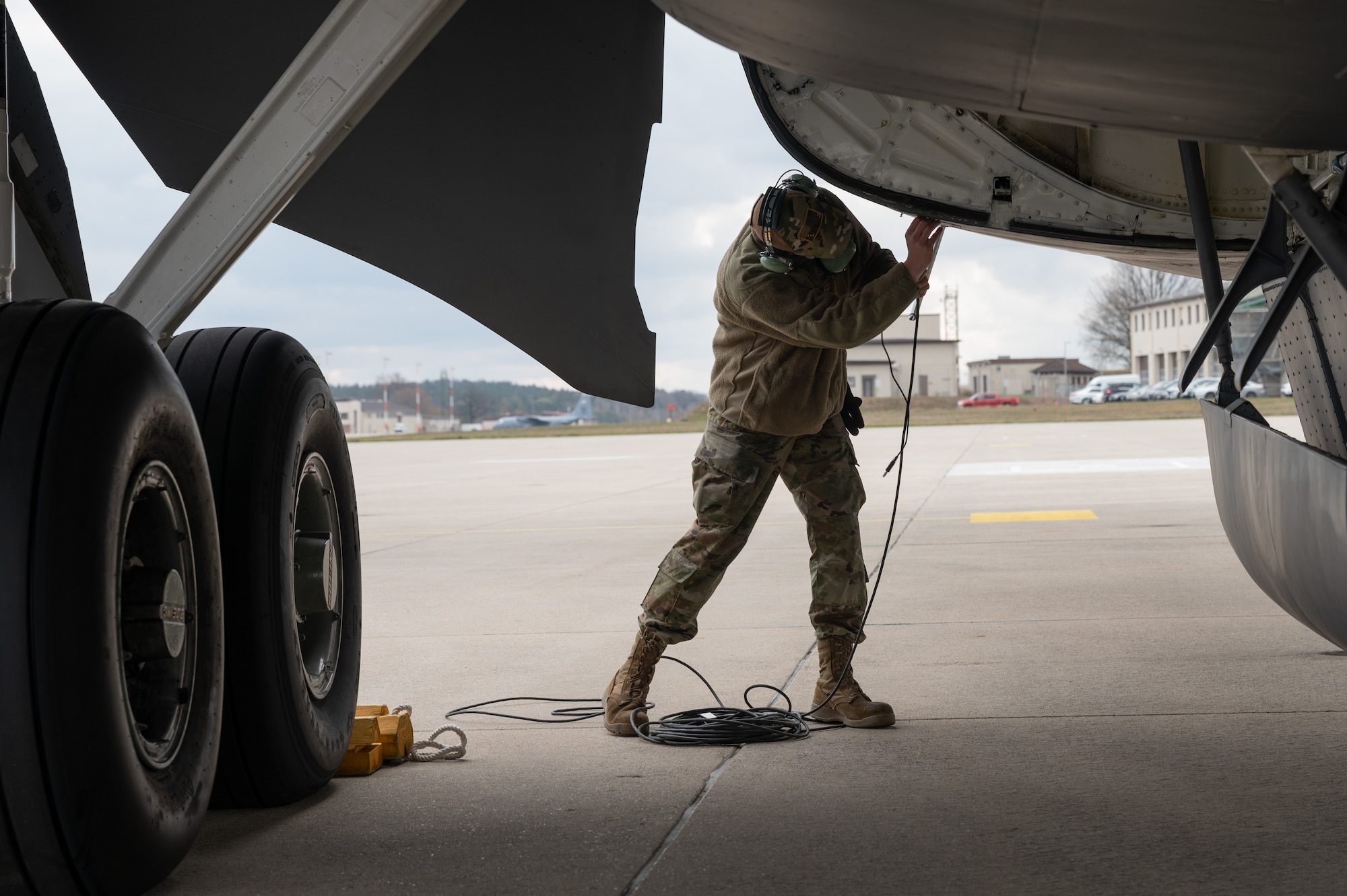 Airman plugging a cord into an aircraft.