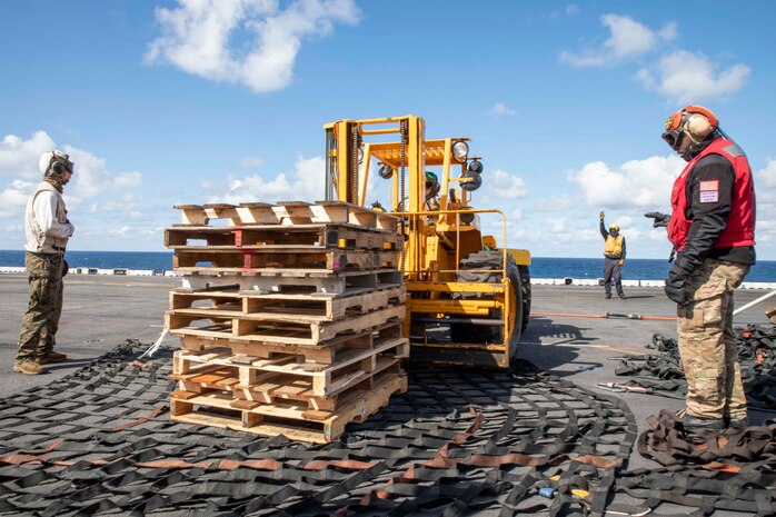 Sailors assigned to the Wasp-class amphibious assault ship USS Iwo Jima (LHD 7) and Marines from the 24th Marine Expeditionary Unit (24th MEU) prepare a pallet stack for offload during a replenishment-at-sea, April 11, 2021.