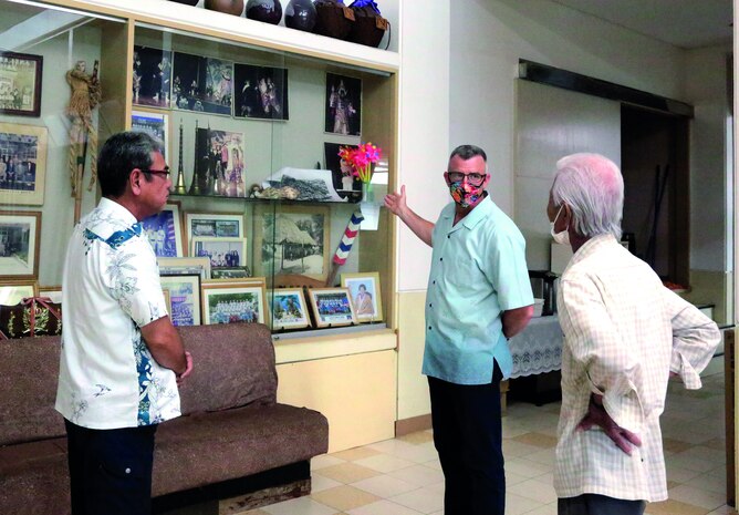 Col. Perry talks to Kenei Tanahara (left), Kushi district mayor, and Tsuneo Shimabukuro about the pictures in the display.