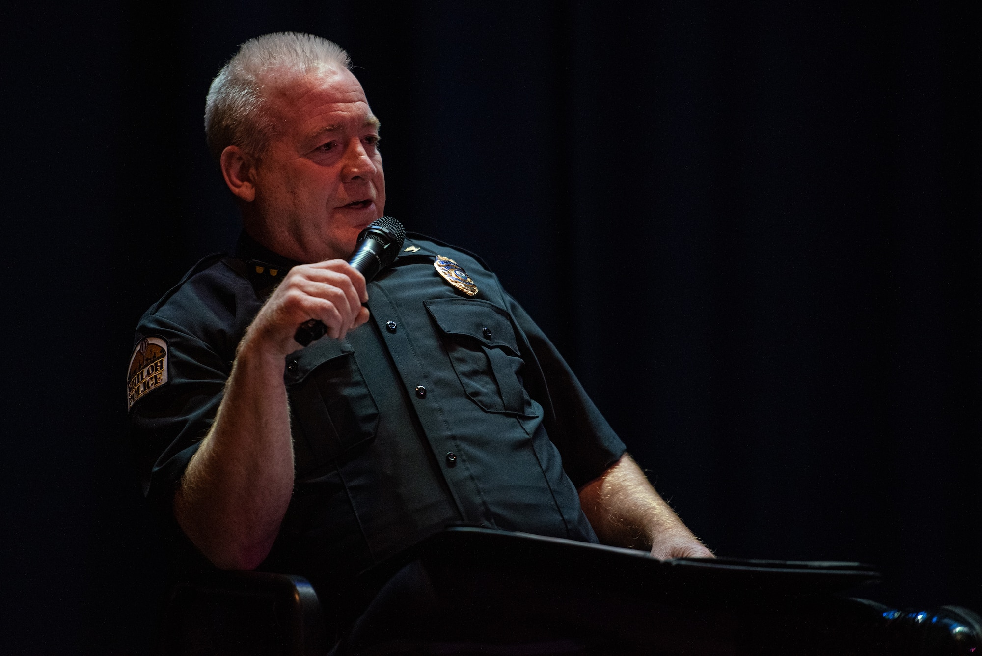 Police officer speaking into a microphone.