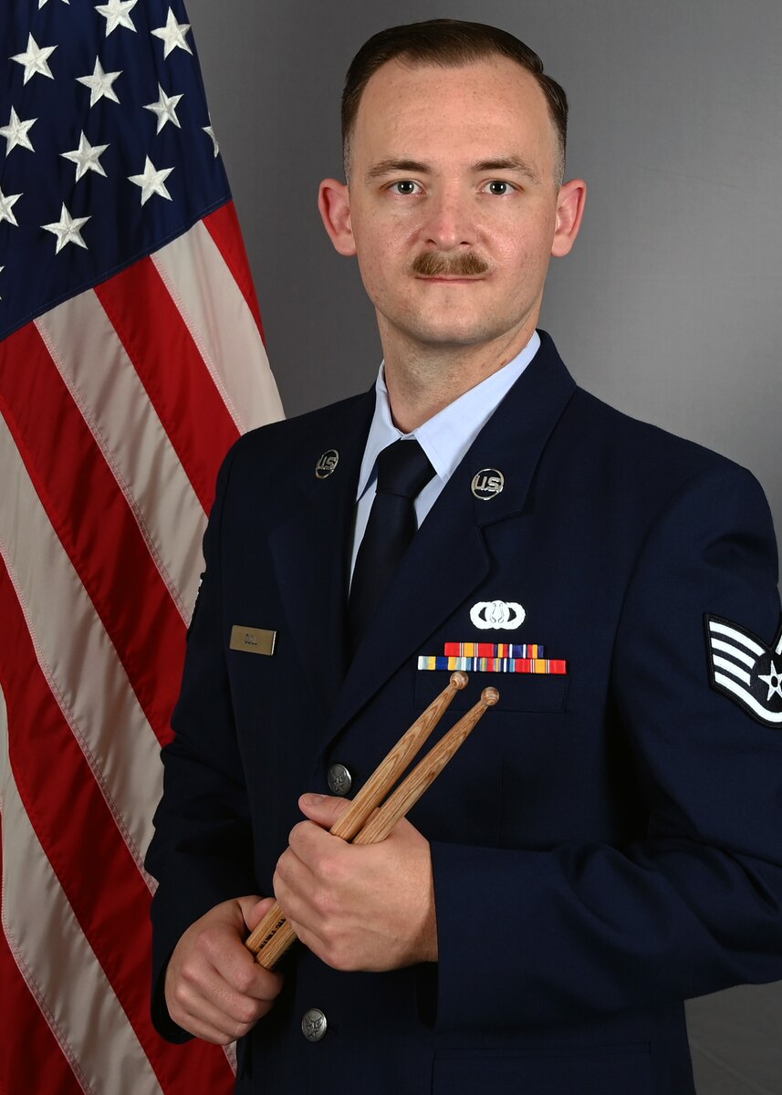Official photo of SSgt Levi Cull, percussionist.  SSgt Cull performs with the Concert Band and Heritage Brass, two of six ensembles with the Heritage of AMerica Band, Langley AFB, VA.  SSgt Cull is wearing blue service dress in front of an American flag.