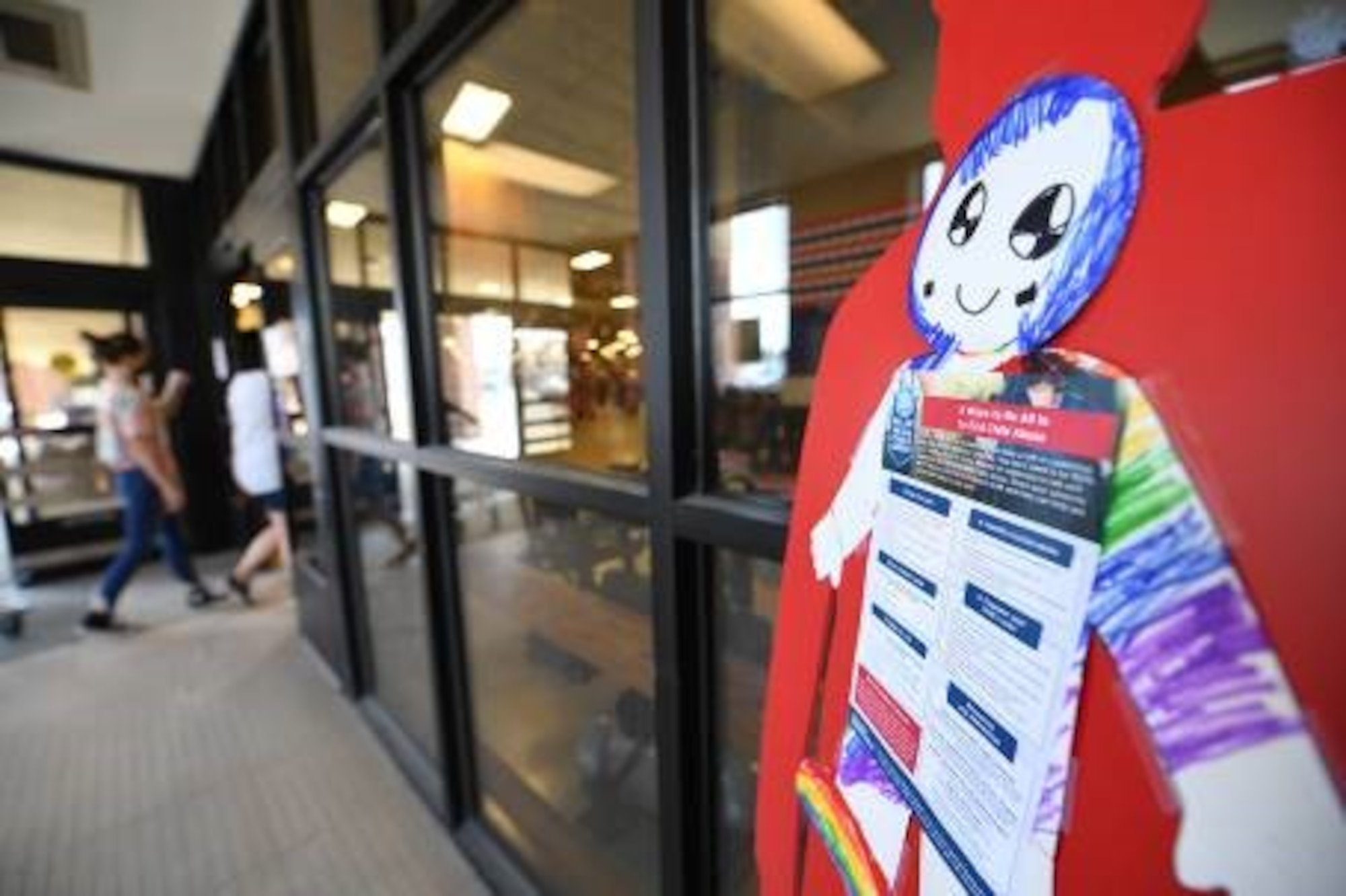 A Commissary customer walks by a Child Abuse Prevention Month display at Hanscom Air Force Base, Mass., April 21. The silhouettes placed around the installation were colored and decorated by children from the Hanscom youth programs and each resources for reporting and preventing child abuse. (U.S. Air Force photo by Mark Herlihy)