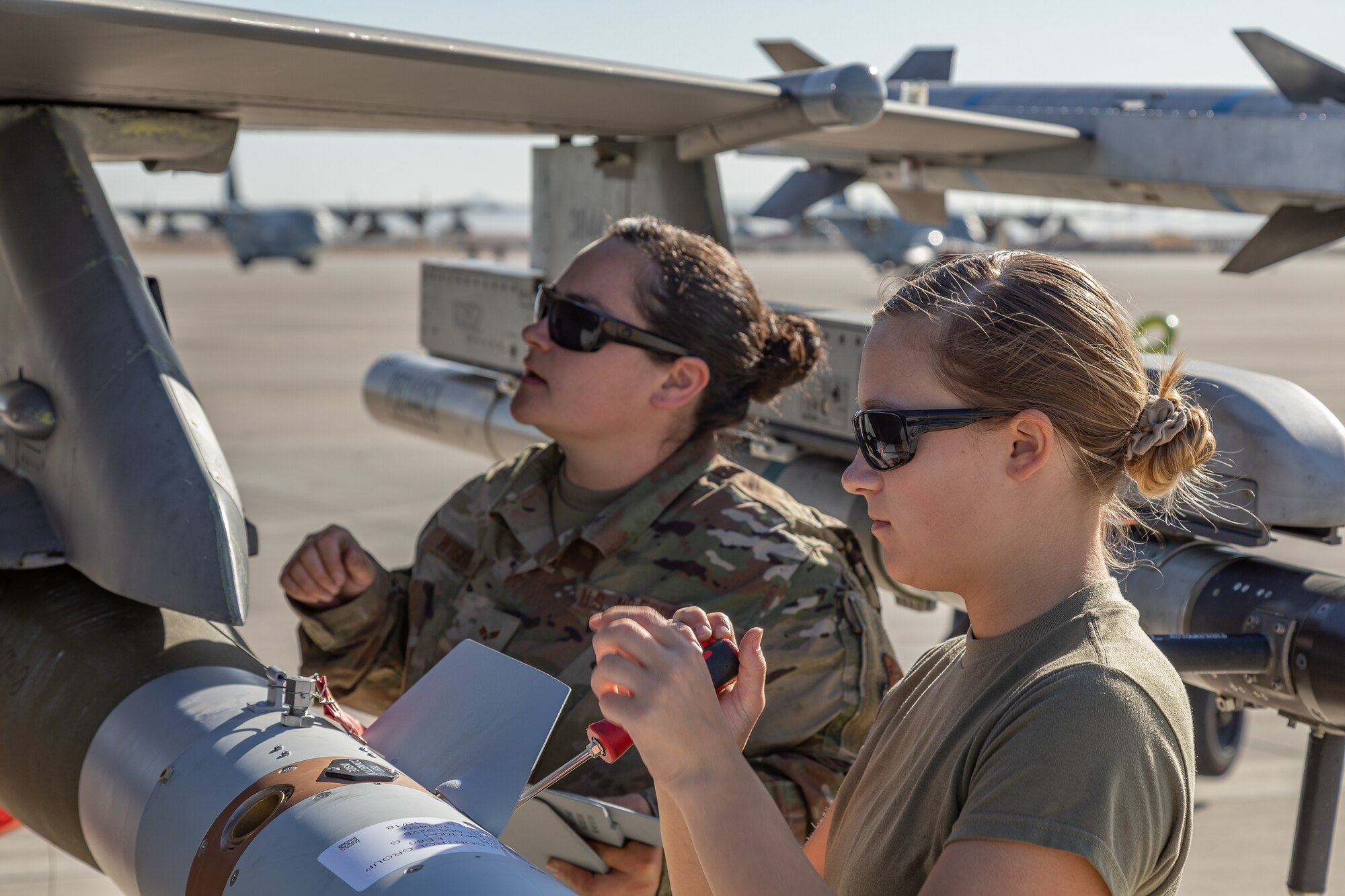 Two airmen equip an F-16 Fighting Falcon with a GBU-12 Paveway II bomb.