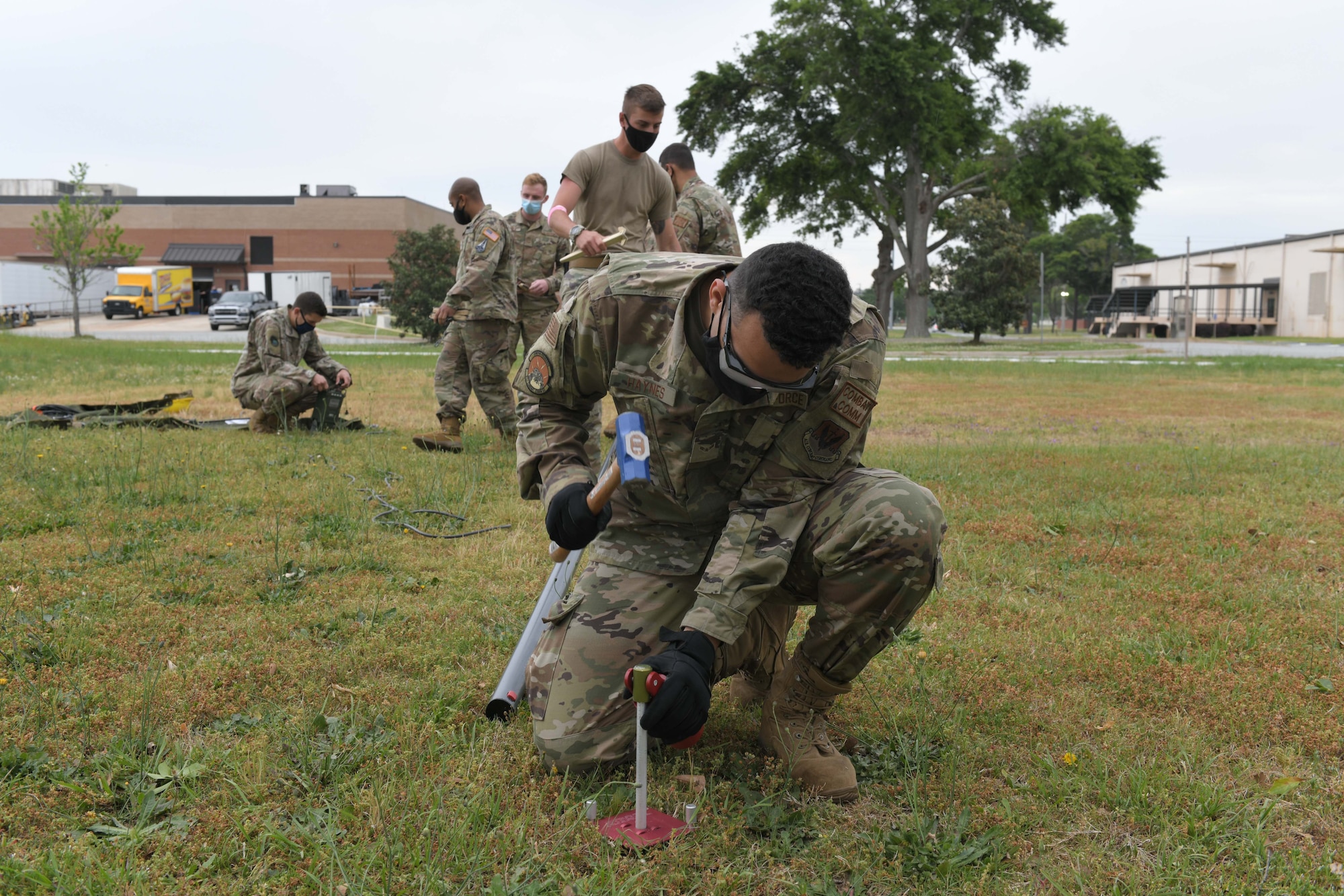 Photo shows Airman hammering spike into ground.