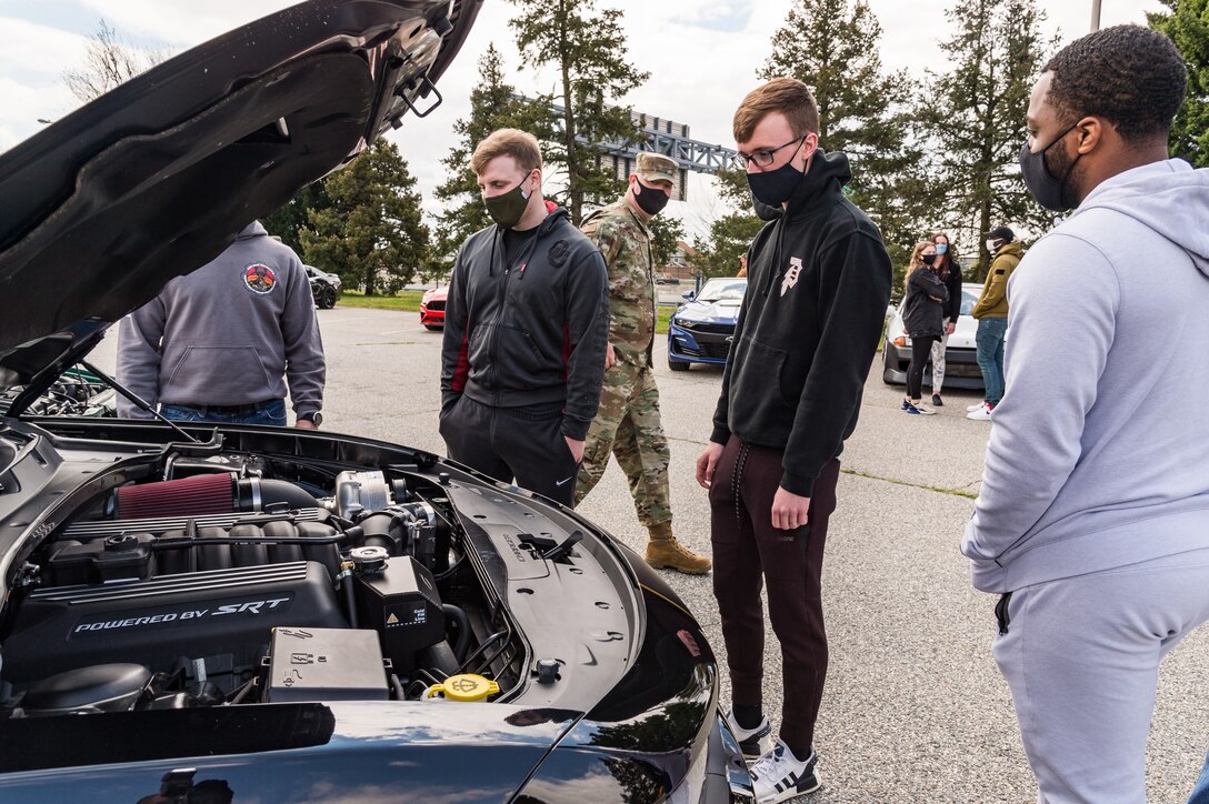 Team Dover members observe a car engine during the Wingman Day car and bike show on Dover Air Force Base, Delaware, April 16, 2021. Thirty-six cars and four motorcycles entered the show. (U.S. Air Force photo by Roland Balik)