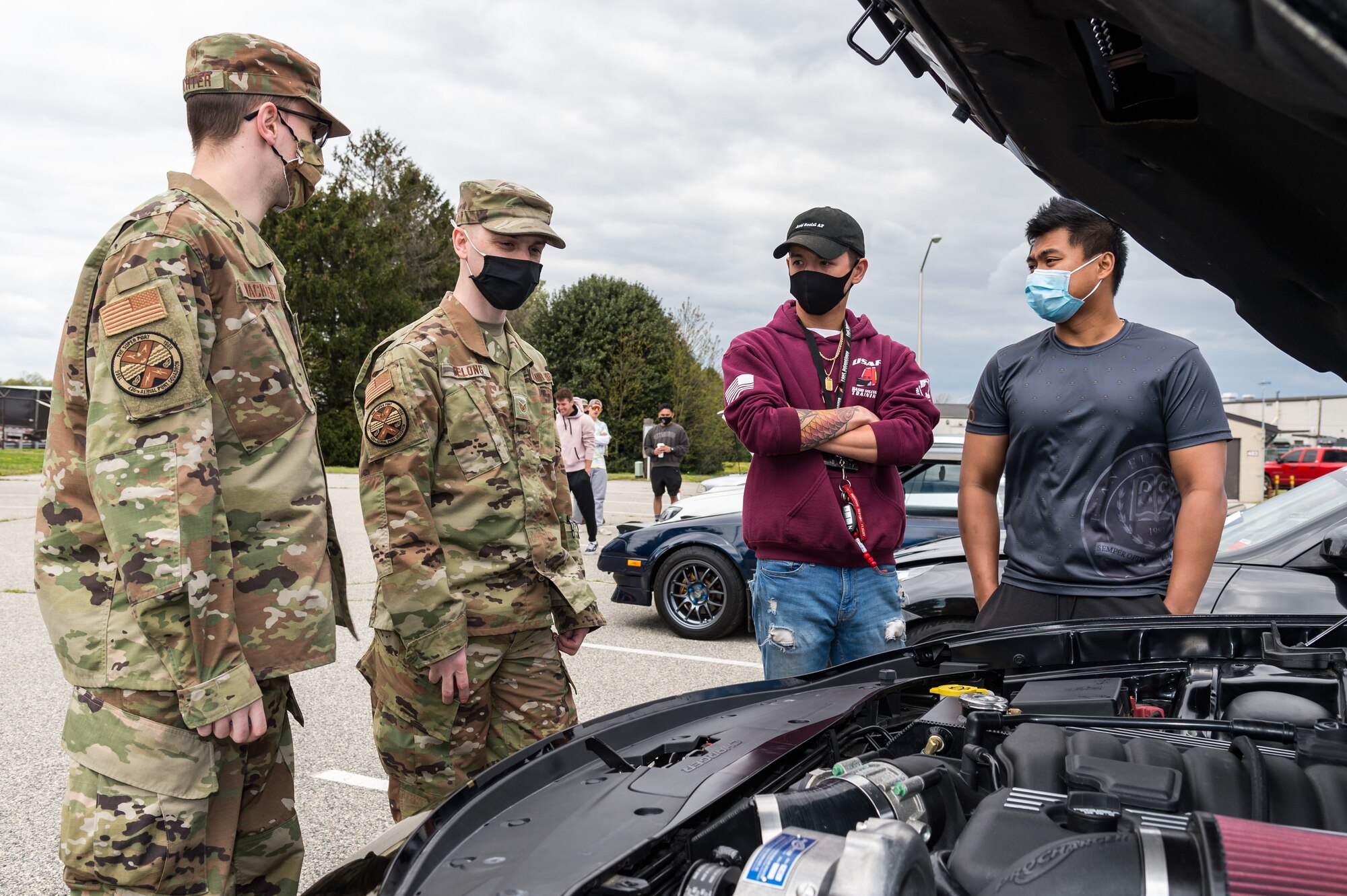 Team Dover members discuss a car engine during the Wingman Day car and bike show on Dover Air Force Base, Delaware, April 16, 2021. Thirty-six cars and four motorcycles entered the show. (U.S. Air Force photo by Roland Balik)