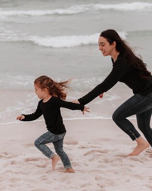 Woman and girl run on the beach