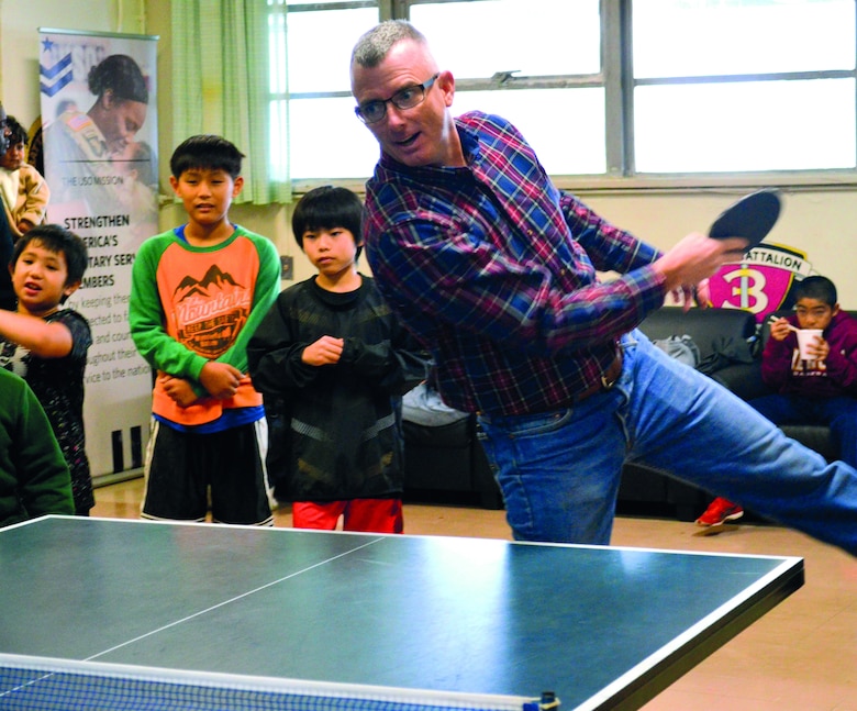 Col. Perry plays table tennis with a local child at the 38th Camp Schwab/USO Christmas Children’s Day in Camp Schwab USO Dec. 7, 2019.