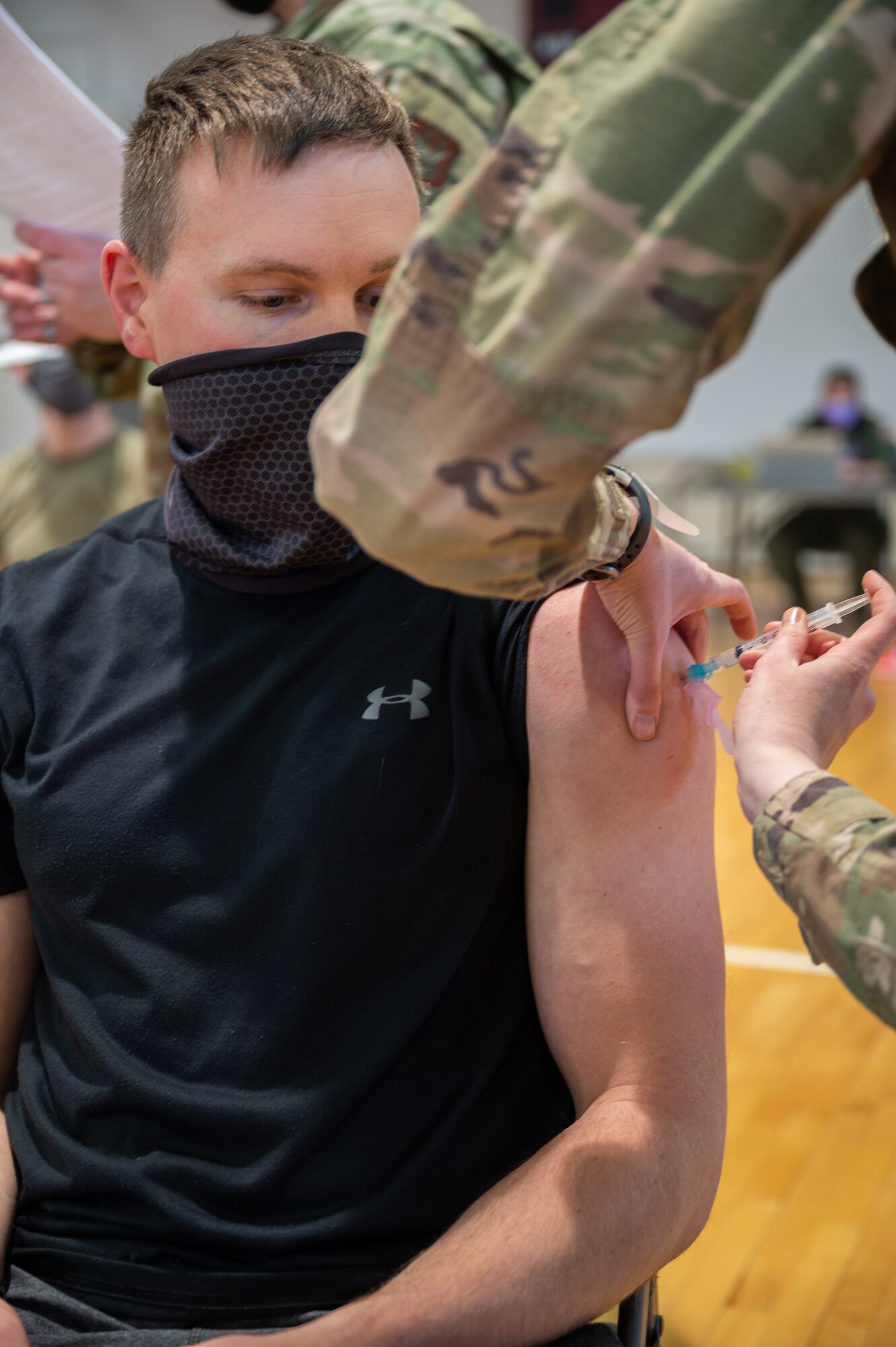 A man looks down at his arm as he receives a vaccination shot